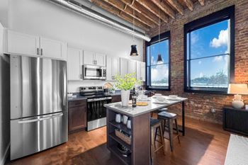 A kitchen with a stainless steel refrigerator and wooden floors.at Plant 1 Lofts, N. Newton, IA 50208  